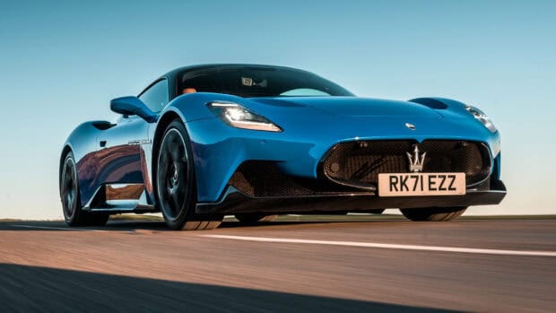 A blue Maserati Mc20 is driving on a road under clear blue sky, HD Desktop Wallpaper