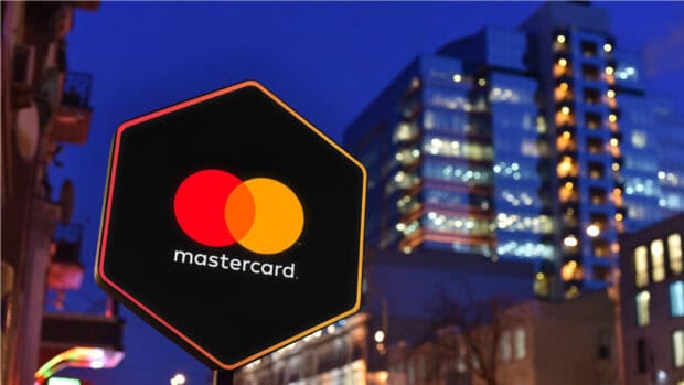 A Mastercard logo sign glows brightly against a cityscape at dusk with lights, HD Desktop Wallpaper