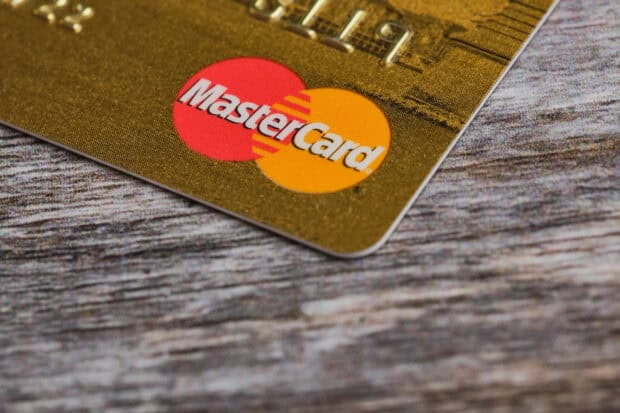 A close up of a Mastercard logo on a gold card placed on a wooden surface, 2K Desktop Wallpaper