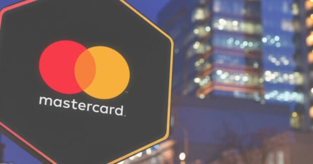 A Mastercard logo sign is displayed on a black hexagonal board with city lights in the background, HD Desktop Wallpaper