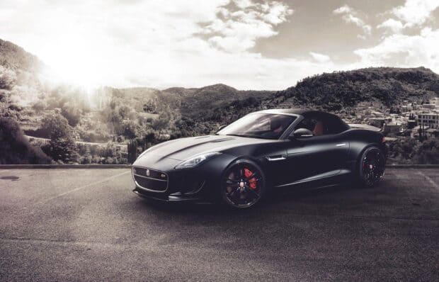A matte black Jaguar F Type is parked with hills and a cloudy sky in the background, HD Desktop Wallpaper