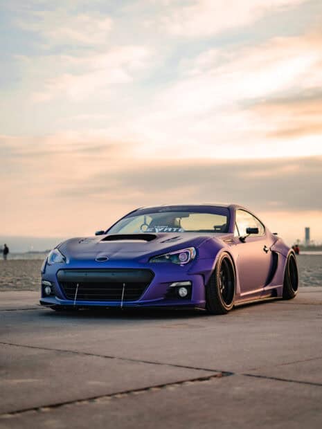A matte purple Subaru Brz is parked on a concrete surface with a cloudy sky at sunset, 2K Mobile Wallpaper