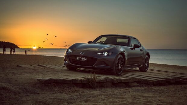 A Mazda MX 5 Miata is parked on a wooden platform near the beach during sunset, HD Desktop Wallpaper