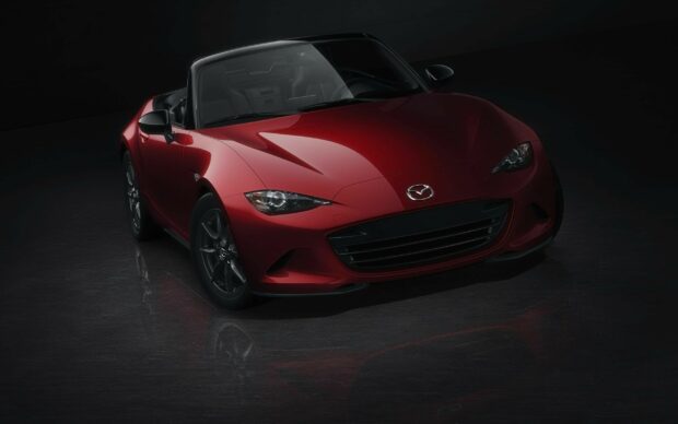The red Mazda MX 5 Miata is shown in a dark studio setting with reflections on the floor, 2K Desktop Wallpaper