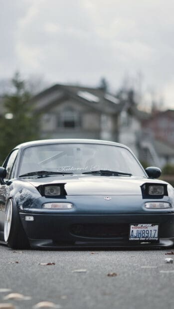 A Mazda MX 5 Miata is shown parked on a street with houses in the background, HD Phone Wallpaper