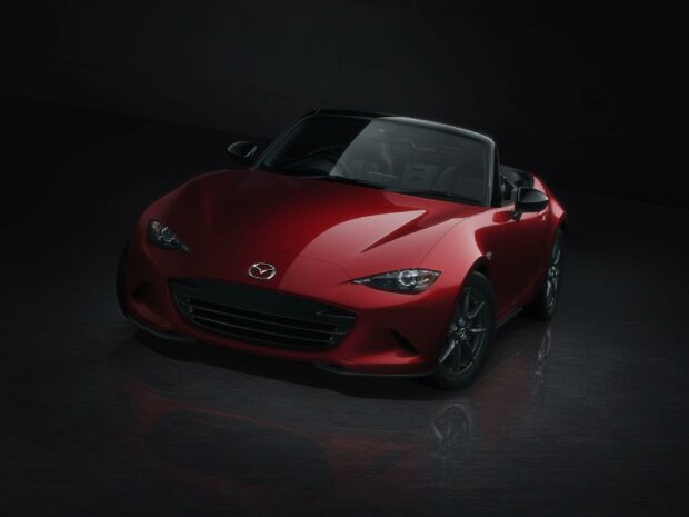 A red Mazda MX 5 Miata convertible car with sleek design is shown in a dark setting, 2K Desktop Wallpaper