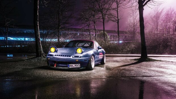 A Mazda Mx 5 Miata with yellow headlights is parked on a wet street at night surrounded by bare trees, HD Desktop Wallpaper