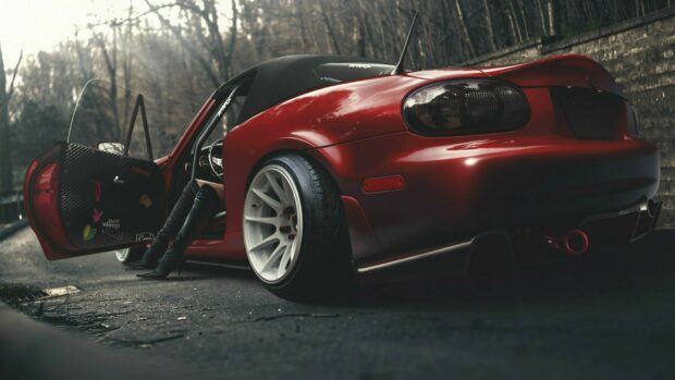 A red Mazda Mx 5 Miata with an open door and a person sitting inside is parked on a forest road, HD Desktop Wallpaper