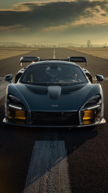 A sleek McLaren Senna is parked on an empty runway during sunset with dramatic clouds above, 4K Mobile Wallpaper