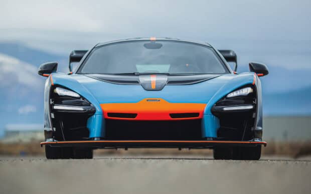 A blue and orange Mclaren Senna is shown from the front on a road with a blurred background, HD Desktop Wallpaper