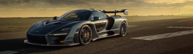 A McLaren Senna is parked on an empty race track during sunset with wind turbines in the background, 4K Desktop Wallpaper