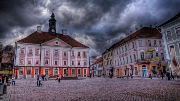 People walk in a medieval town square under cloudy skies in Estonia, 2K Desktop Wallpaper