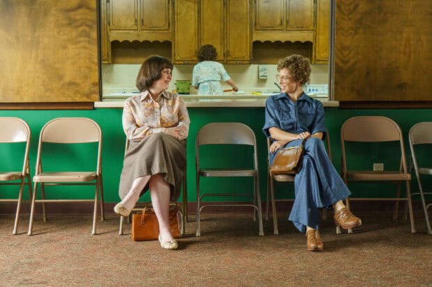 Two women chatting while sitting in chairs with Melanie Lynskey in a vintage setting, 2K Desktop Wallpaper
