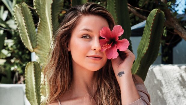 Melissa Benoist holds a pink flower near her eye while standing in front of green cacti, 4K Desktop Wallpaper