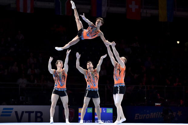 A group of men performing an acrobatic gymnastics routine during a competition, HD Desktop Wallpaper