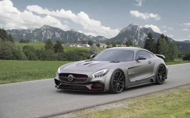 A silver Mercedes Benz AMG GT is parked on a mountain road surrounded by green fields and scenic peaks, HD Desktop Wallpaper