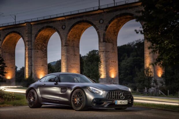 A Mercedes Benz AMG GT is parked on the road in front of a lit stone viaduct during dusk, 2K Desktop Wallpaper