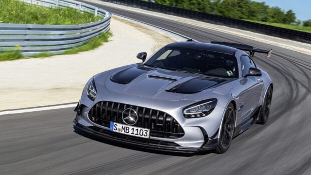 A silver Mercedes Benz AMG GT is speeding on a curved racing track under a clear sky, HD Desktop Wallpaper