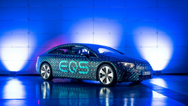 A Mercedes Benz EQS electric car is displayed against a blue lit wall in a showroom, HD Desktop Wallpaper