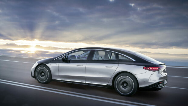 A silver Mercedes Benz Eqs is driving on the highway under a cloudy sunset sky, 2K Desktop Wallpaper