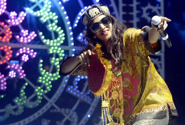 Mia rapper performing on stage with a microphone and vibrant lights, 2K Desktop Wallpaper