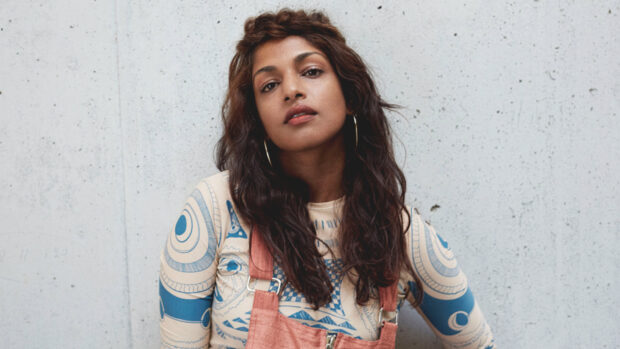 A portrait of Mia rapper wearing artistic clothing and hoop earrings against a wall, HD Desktop Wallpaper