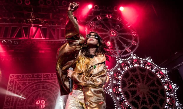 Mia rapper performing on stage with microphone and gold outfit, HD Desktop Wallpaper