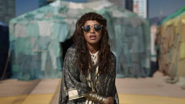 Mia rapper wears sunglasses and a patterned outfit in an outdoor setting, HD Desktop Wallpaper