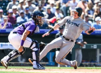 A Miami Marlins player is sliding into a base while an opposing catcher prepares to tag him during a game, 2K Desktop Wallpaper