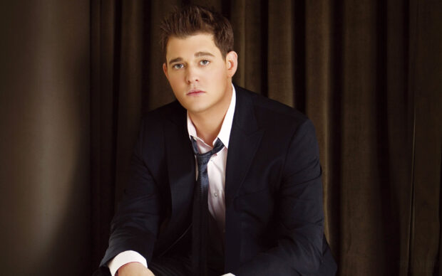A portrait of Michael Buble wearing a dark suit and tie sitting in front of a curtain, HD Desktop Wallpaper