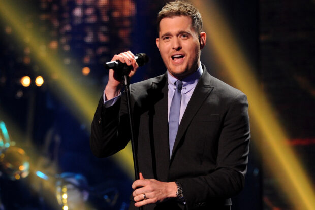 Michael Buble is performing live holding a microphone in a black suit and blue tie, HD Desktop Wallpaper