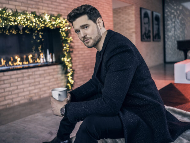 Michael Buble sitting indoors holding a mug near decorated fireplace with lights, 2K Desktop Wallpaper