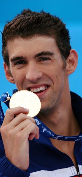 Michael Phelps is smiling while holding a gold medal at a swimming competition, 2K Phone Wallpaper