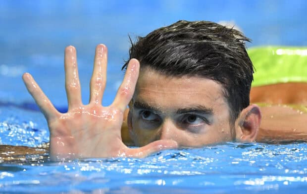Michael Phelps showing five fingers while swimming in the pool during competition, 2K Desktop Wallpaper
