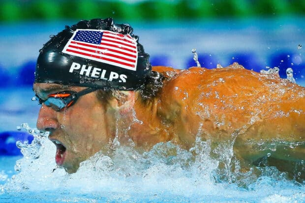 Michael Phelps swimming intensely during a race with water splashing around him, 2K Desktop Wallpaper