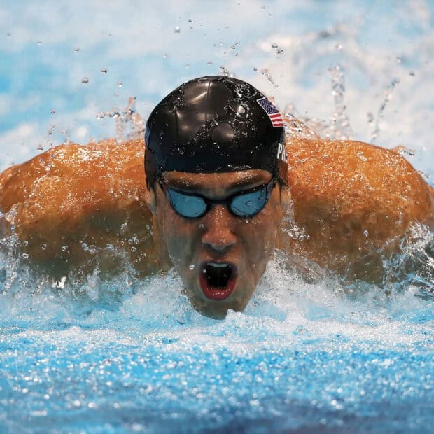 Michael Phelps swims powerfully in a swimming race wearing a black cap, HD Desktop Wallpaper