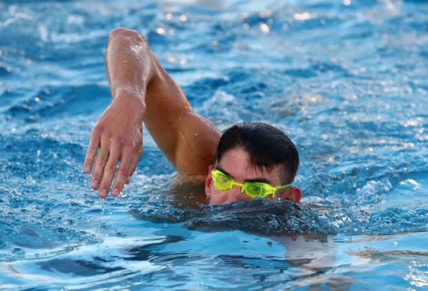 Michael Phelps swimming laps wearing goggles in a clear blue pool, 2K Desktop Wallpaper