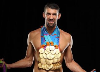 Michael Phelps is shown smiling wearing many Olympic gold medals around his neck against a black background, HD Desktop Wallpaper