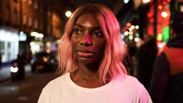 A close up portrait of Michaela Coel with pink hair in a city at night, HD Desktop Wallpaper