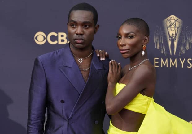 Michaela Coel attends the Emmy Awards wearing a vibrant yellow dress with a male companion, 2K Desktop Wallpaper