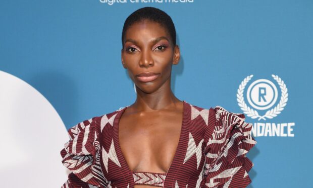 Michaela Coel wears a detailed patterned dress posing against a blue background, HD Desktop Wallpaper