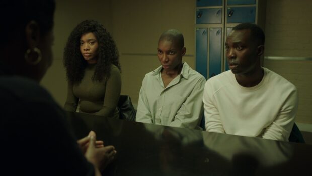 Michaela Coel is seen in a serious conversation with two other people in a dimly lit room, HD Desktop Wallpaper