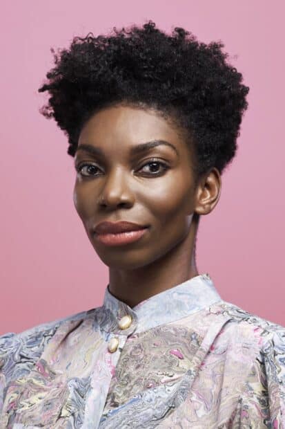A close up portrait of Michaela Coel with natural makeup and a patterned blouse, 2K Phone Wallpaper