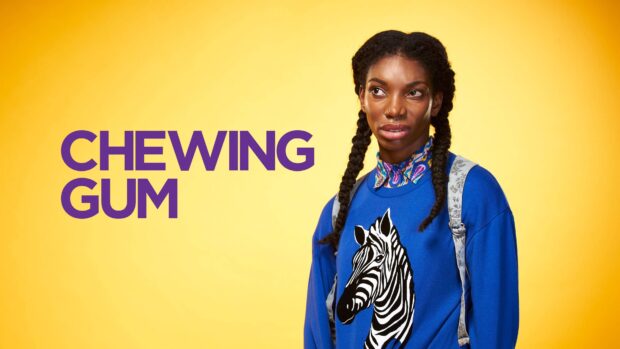 Michaela Coel stands in a blue sweater with a zebra print on yellow, 4K Desktop Wallpaper