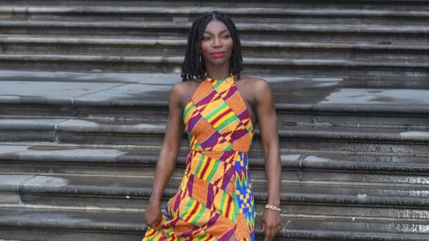 Michaela Coel is standing in front of stone steps wearing a colorful patterned dress, HD Desktop Wallpaper
