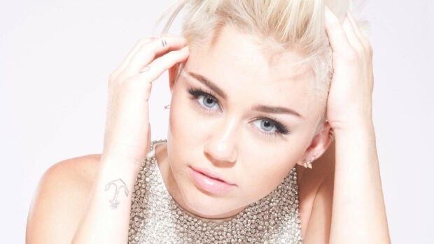 A close up portrait of Miley Cirus with blonde hair and blue eyes wearing a sparkling top, 2K Desktop Wallpaper