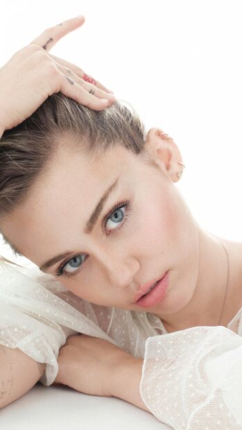 A close up portrait of Miley Cirus with blue eyes resting on her arm, 2K Mobile Wallpaper
