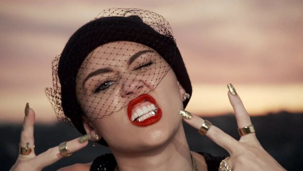 Miley Cirus shows a fierce expression wearing a black hat with a net on her face, HD Desktop Wallpaper