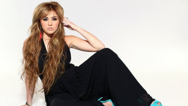 Miley Cyrus poses in a black dress with long hair and blue shoes, 4K Desktop Wallpaper