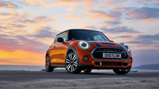 A Mini Cooper car is parked near the ocean under a colorful sunset sky, HD Desktop Wallpaper